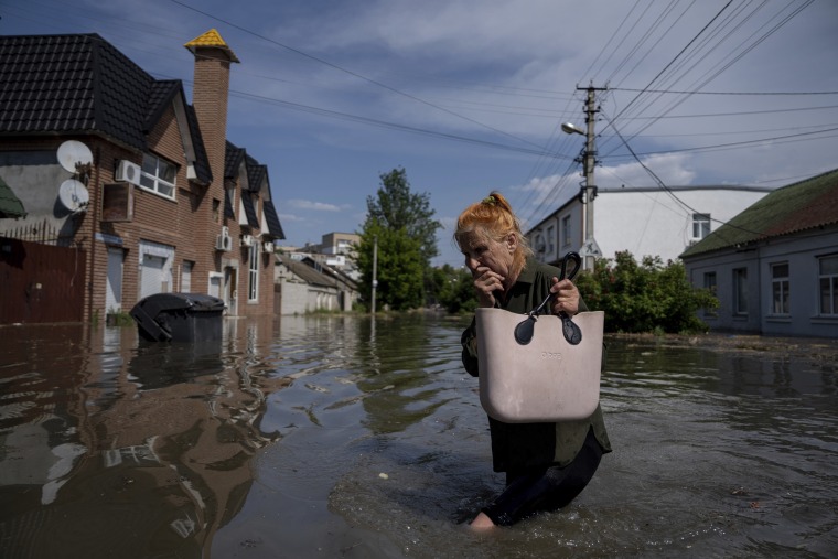 A local resident makes her way through a flooded road after the walls of the Kakhovka dam collapsed overnight, in Kherson, Ukraine