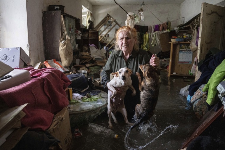 Local resident Tetiana holds her pets, Tsatsa and Chunya, as she stands inside her house that was flooded in Kherson, Ukraine