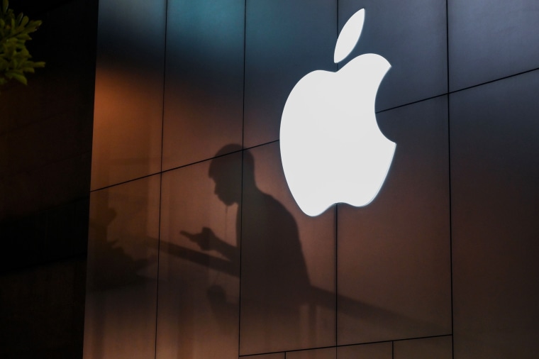 The shadow of a man is cast on the wall of an Apple store as he uses his mobile phone in Beijing on August 26, 2019. 