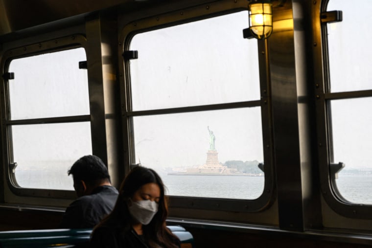 A passenger wearing a face mask rides the Staten Island Ferry past the Statue of Liberty during heavy smog in New York on June 6, 2023. Smoke from Canada's wildfires has engulfed the Northeast and Mid-Atlantic regions of the US, raising concerns over the harms of persistent poor air quality.