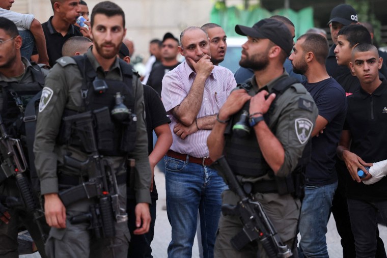 Israeli security forces and onlookers gather in front of a car wash where five Arab Israelis were shot dead, in the village of Yafia, west of Nazareth, on June 8, 2023.