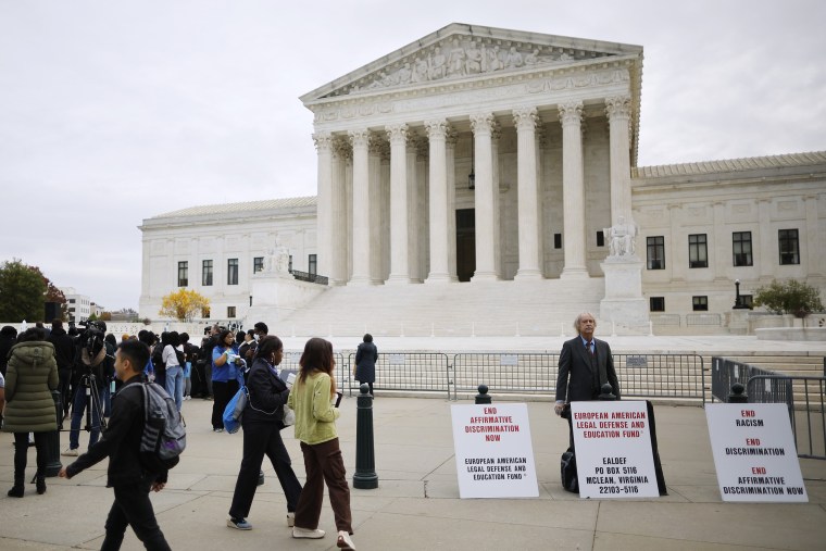 An opponent to affirmative action in higher education stands next to a rally of proponents at the supreme court