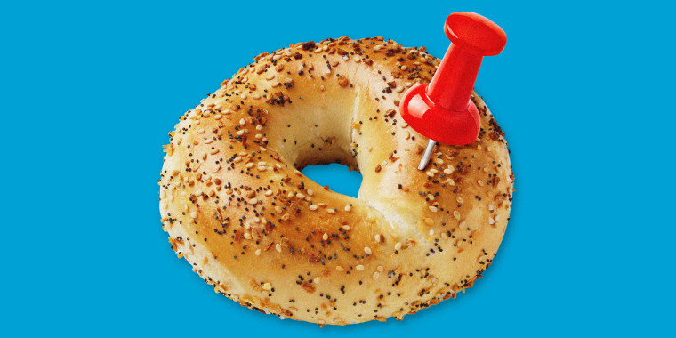 Photo illustration of an everything bagel with a red locator pin stuck in it.