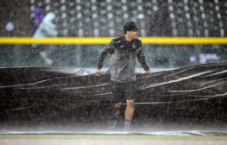 Image: A member of the grounds crew pulls the tarpaulin as a heavy rain swamps Coors Field in the bottom of the ninth inning of a baseball game between the San Diego Padres and the Colorado Rockies, on June 11, 2023, in Denver. 