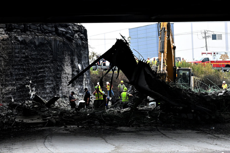 Workers inspect and clear debris from a section of the bridge that collapsed on Interstate 95 after an oil tanker explosion in Philadelphia