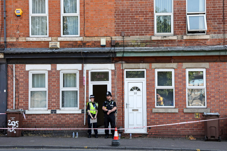 Police officers stand outside a house that was raided in Nottingham, England, following a 'major incident' in which three people were found dead on June 13, 2023.
