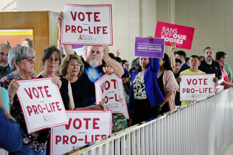 Protesters on both sides of the abortion debate hold signs May 16, 2023, in Raleigh, N.C., outside the Senate gallery.