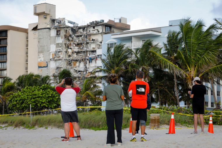 People observe the wreckage of a partially collapsed building in Surfside, Fla.