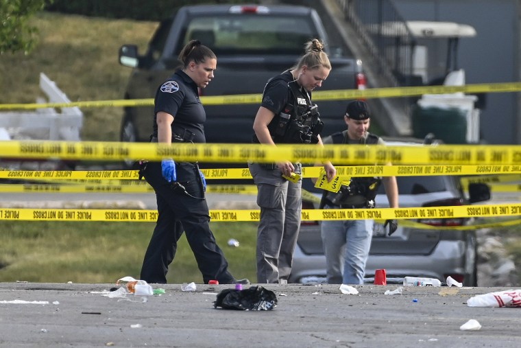 Investigators look over the scene of an overnight mass shooting at a strip mall in Willowbrook, Ill., on June 18, 2023.