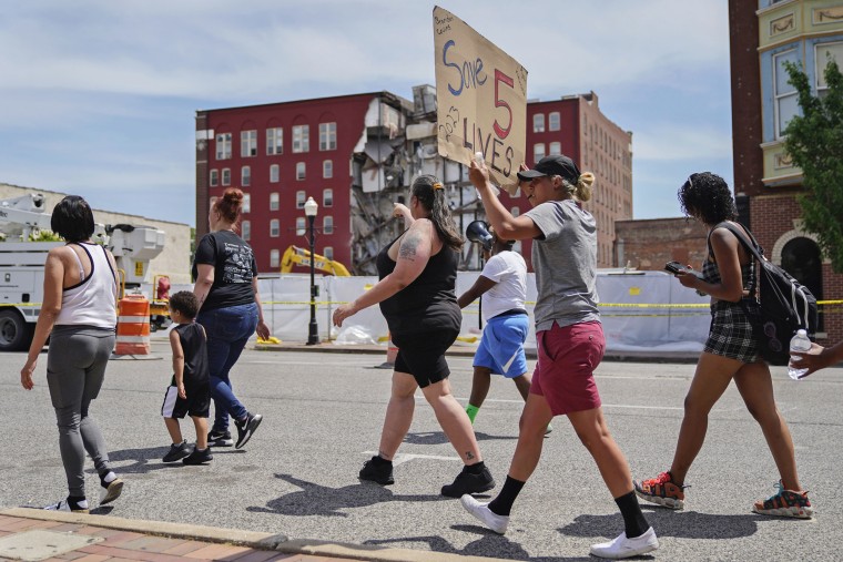 Protesters march in the street on May 31, 2023, at the scene where on an apartment building partially collapsed in Davenport, Iowa.