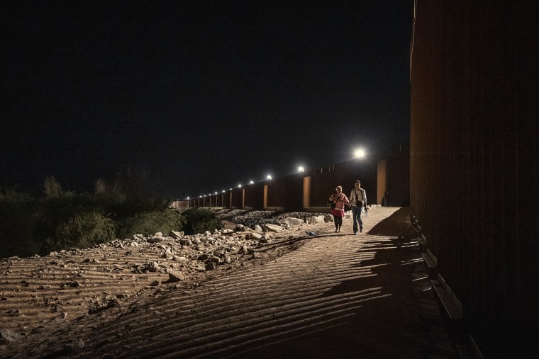 Migrants walk along the U.S.-Mexico border fences on June 6, 2023 in Yuma, Ariz.