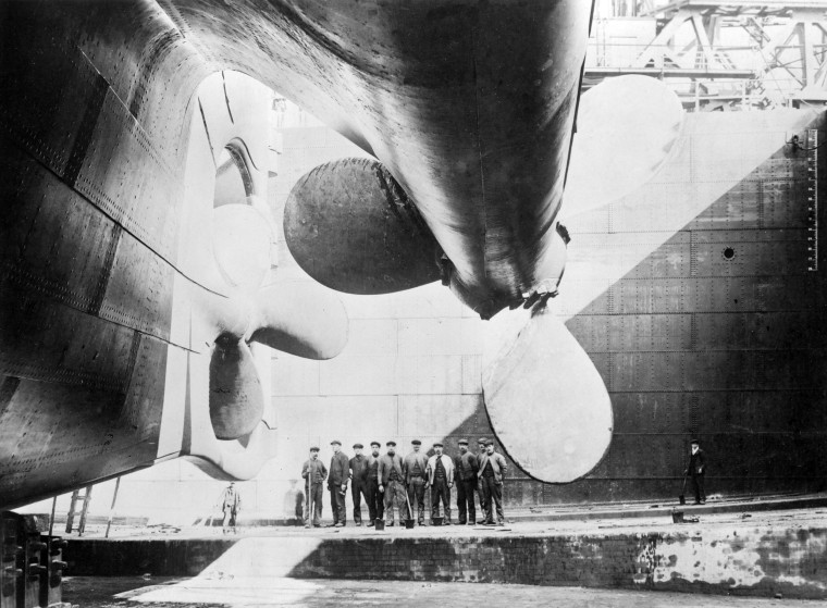 Image:Workmen stand under one of Titanic's propellers in 1911.