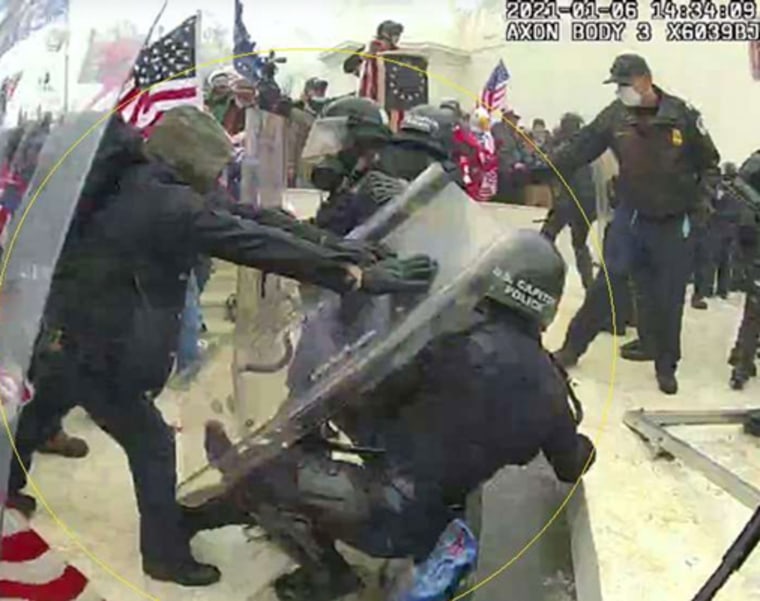 Brian Christopher Mock, left, shoves a Capitol police officer to the ground on Jan. 6, 2021.
