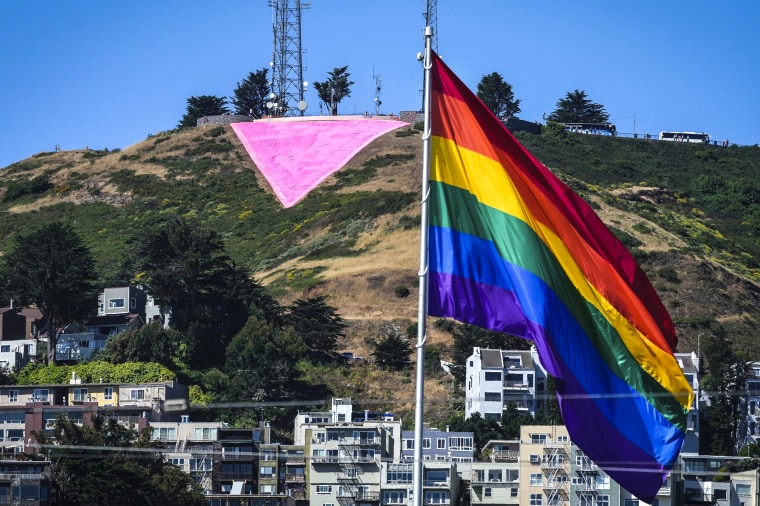 Image: A pink triangle is seen on top of Twin Peaks behind the Castro district rainbow flag in San Francisco on June 20, 2023.