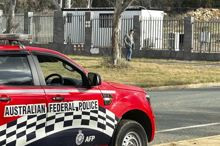 A man walks along a fence that surrounds a a building on the grounds of a proposed new Russian embassy near the Australian Parliament in Canberra where an Australian Federal Police officer observes from his vehicle, Friday, June 23, 2023. 