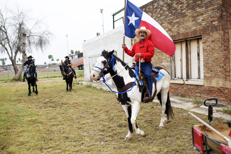 A horseback rider holds a Texas state flag during the Charro Day Grand International Parade