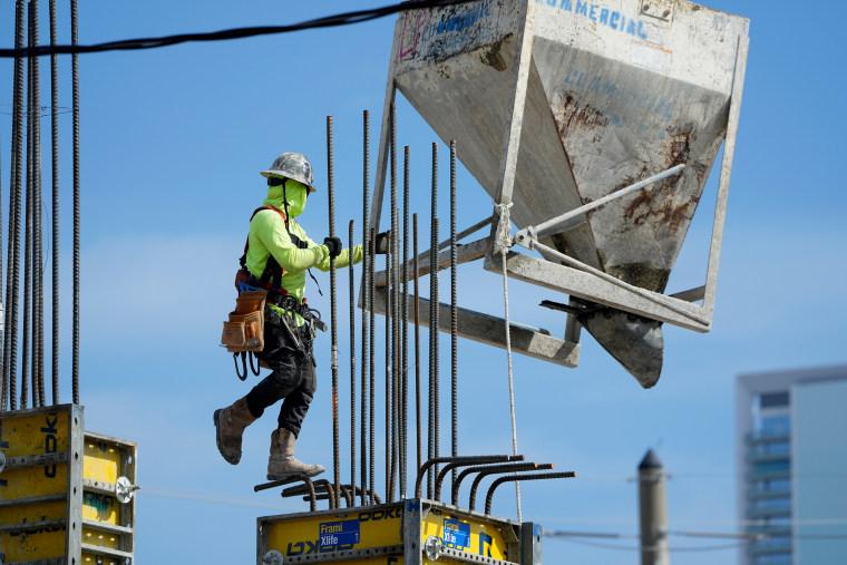 A worker guides a bin into position at a construction site, on Jan. 24, 2023, in Miami.
