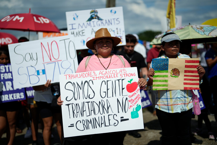 A woman carried a sign that reads: "We are working people, not criminals; we are the ones who harvest the crops; Immokalee farm workers strong" as hundreds gathered on June 1 in Immokalee, Fla., to protest state Senate Bill 1718, which restricts undocumented immigrants.