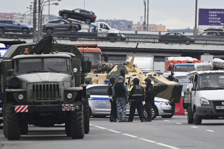An APC and police officers guard the highway at the entrance to Moscow