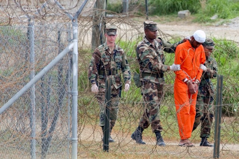 A detainee is led by military police to be interrogated by military officials at Camp X-Ray at the U.S. Naval Base at Guantanamo Bay, Cuba, on Feb. 6, 2002.