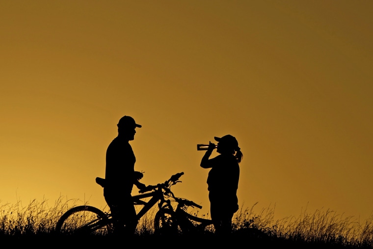 Cyclists take a water break during an evening ride on June 26, 2023, in San Antonio. 