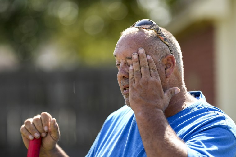 A man pauses to wipes his face while digging fence post holes in Houston June 27, 2023.
