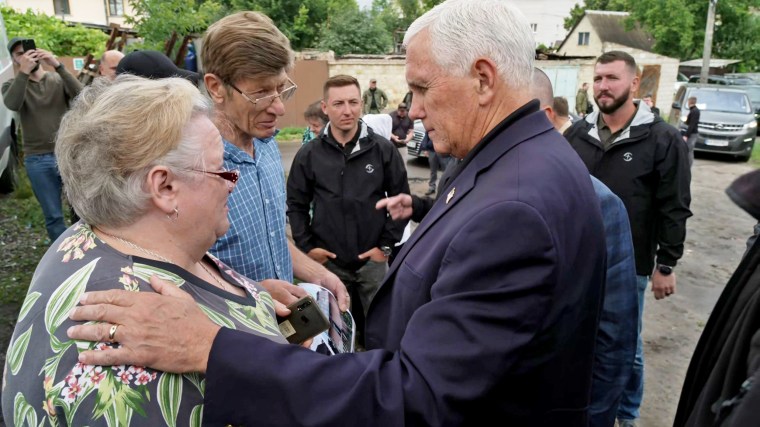 Pence rests his hands on a woman's shoulder as he speaks with her in Irpin, Ukraine