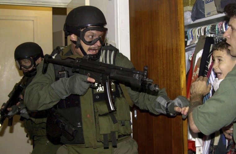 Elian González is held in a closet by one of the two men who rescued him from the ocean as government officials search the home of Lazaro Gonzalez in Miami