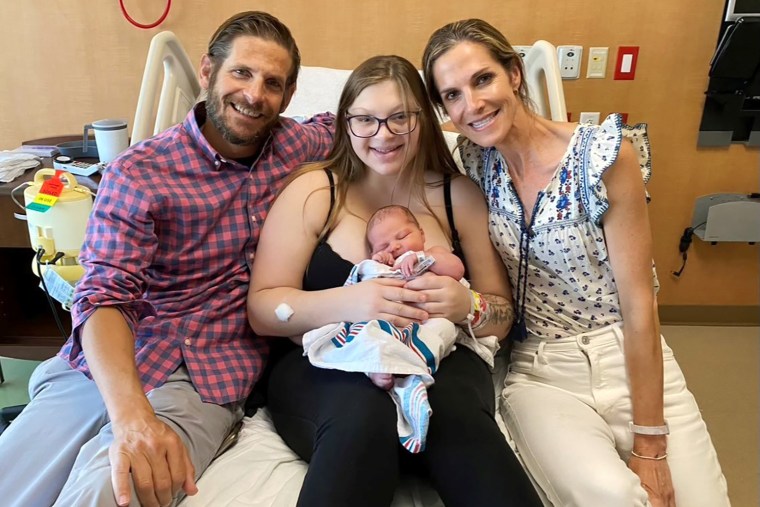 Madelyn holds her baby as they pose with the adoptive parents Nathan Kerr and Laura Robinson.