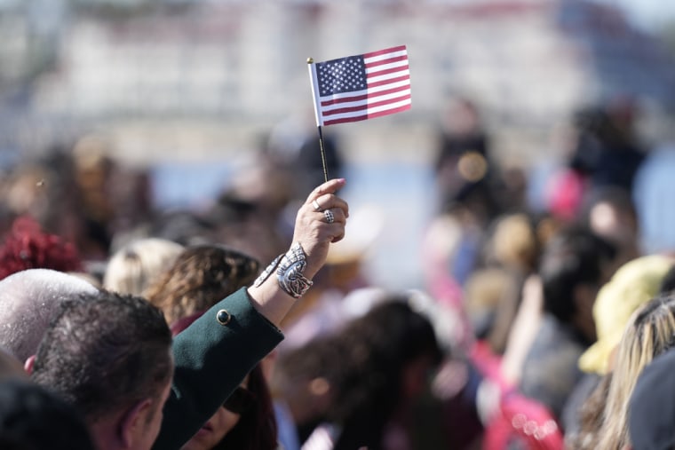 Una mujer ondea una bandera de Estados Unidos durante una ceremonia de naturalización el 15 de febrero de 2023 en San Diego, California.