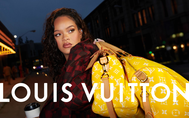 RiHanna holds two yellow luggage bags with the classic Louis Vuitton pattern.