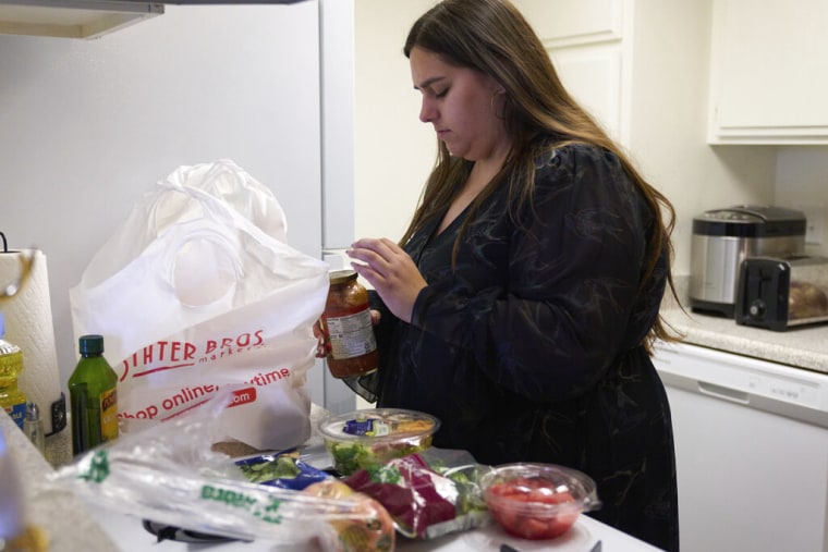 Jaqueline Benitez guarda las compras en su casa en Bellflower, California, el lunes 13 de febrero de 2023. Benitez, de 21 años, quien trabaja como maestra de preescolar, depende de los beneficios de SNAP de California para ayudar a pagar los alimentos.