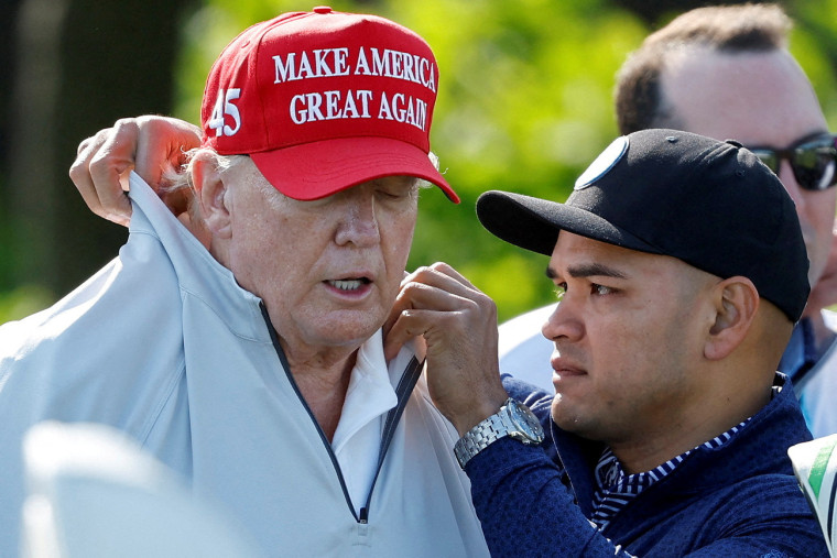 El asistente personal Walt Nauta arregla el cuello de Trump antes de un torneo de golf en Virginia, en mayo de 2023.