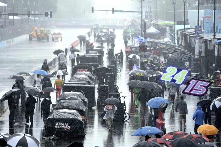 People walk along pit row in the rain before a NASCAR Cup Series auto race at the Grant Park 220 Sunday in Chicago. 