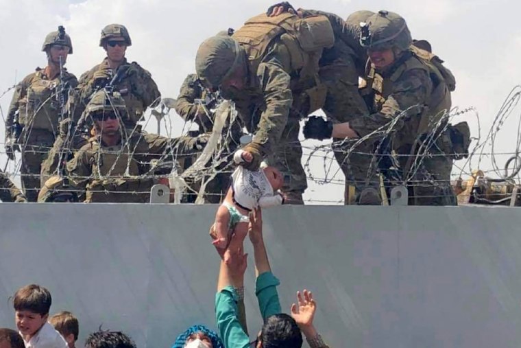 A baby being lifted across a wall at Kabul Airport in Afghanistan by US soldiers in 2021.
