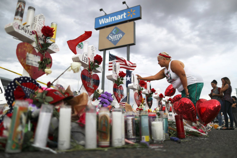 A woman touches a cross at a makeshift memorial for victims of a mass shooting at a Walmart in El Paso, Texas, in 2019.