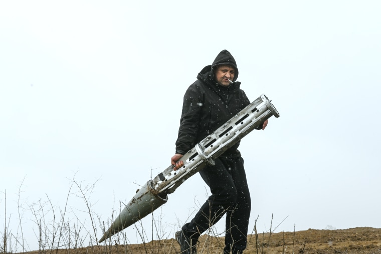 A Ukrainian civilian holds an empty Russian cluster munition rocket