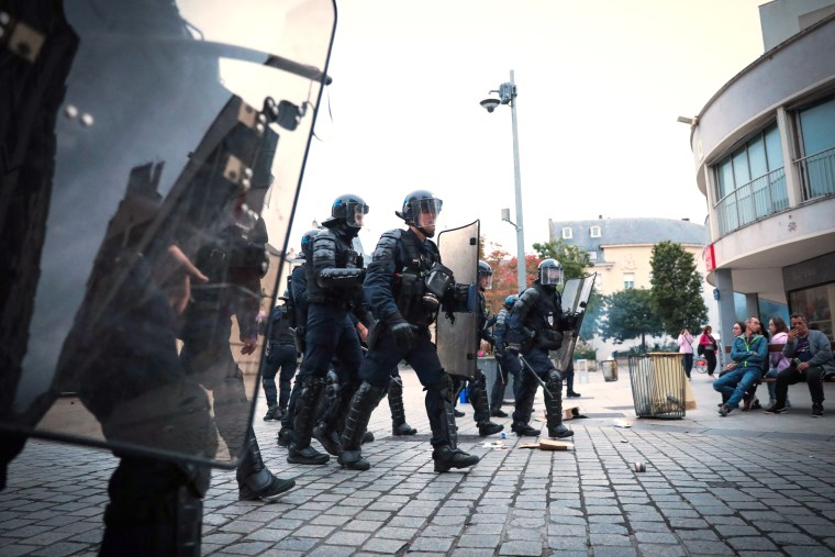 Des policiers anti-émeute français avec des boucliers défilent en patrouillant lors d'une manifestation