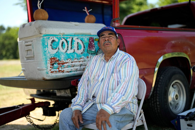 Andres Matamoros sits in the shade as he tries to keep cool while selling fresh fruit and cold coconuts in Houston on June 28, 2023. 