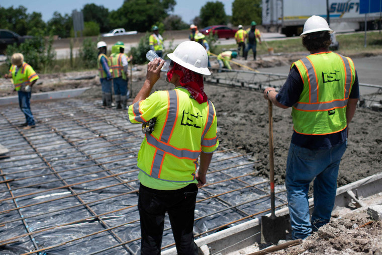 A construction worker takes a sip of water while repairing a road that was damaged from the heat in Houston on June 27, 2023.