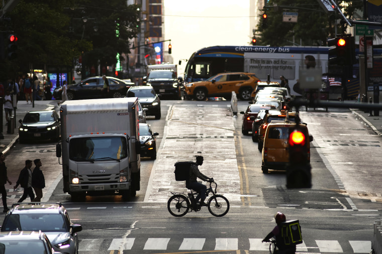 A bicycle delivery person crosses 42nd Street as the sun sets on May 29, 2023, in New York City.