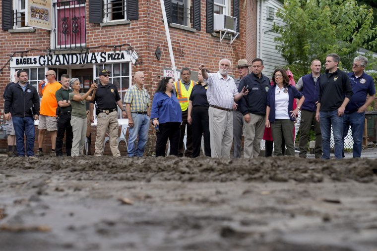 Gov. Kathy Hochul, fourth from right, and an entourage of emergency workers, residents and journalists pass along Main Street on Monday, July 10, 2023, in Highland Falls, N.Y. 