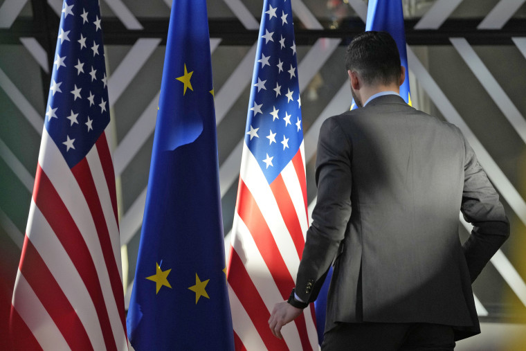 A worker adjusts the U.S. and EU flags at the European Council building in Brussels on April 4, 2023. 