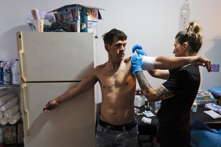 Volunteer registered nurse Jennifer D'Angelo treats Nick Gallagher's skin wounds at the Savage Sisters' community outreach storefront in Philadelphia on May 24, 2023. 
