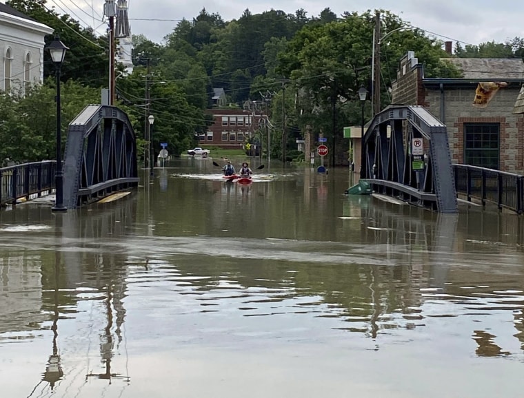 Two kayakers paddle through floodwaters as they approach the School Street Bridge in Montpelier, Vt., on July 11, 2023. 
