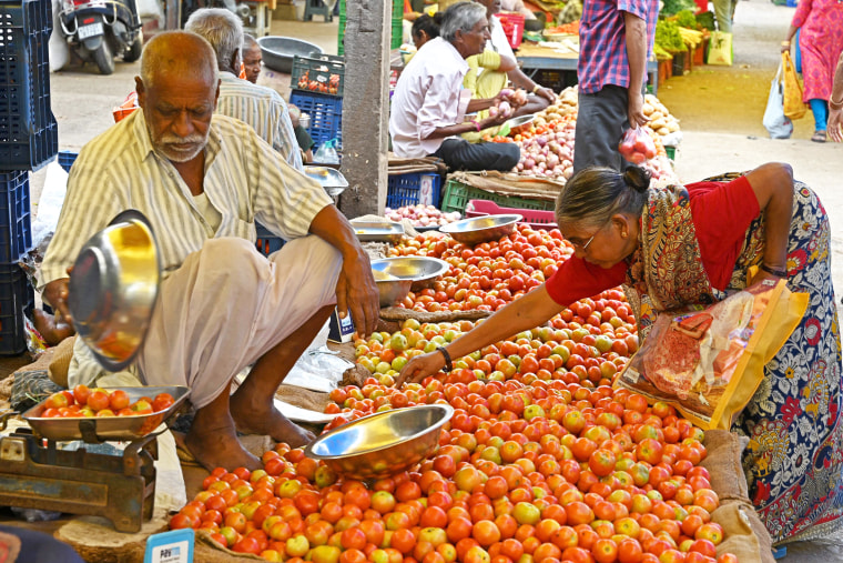 A customer buys tomatoes at a vegetable market in Hyderabad on July 4, 2023.