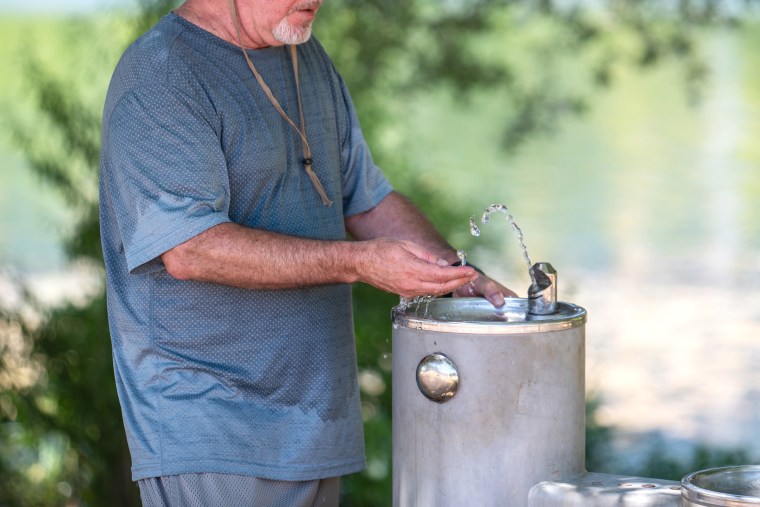 A resident tests the temperature of drinking fountain water during a heatwave in Austin, Texas, US, on Wednesday, July 12, 2023. A record-breaking heat wave is about to send temperatures soaring from California to the Gulf of Mexico, posing health risks and straining power grids for days to come.