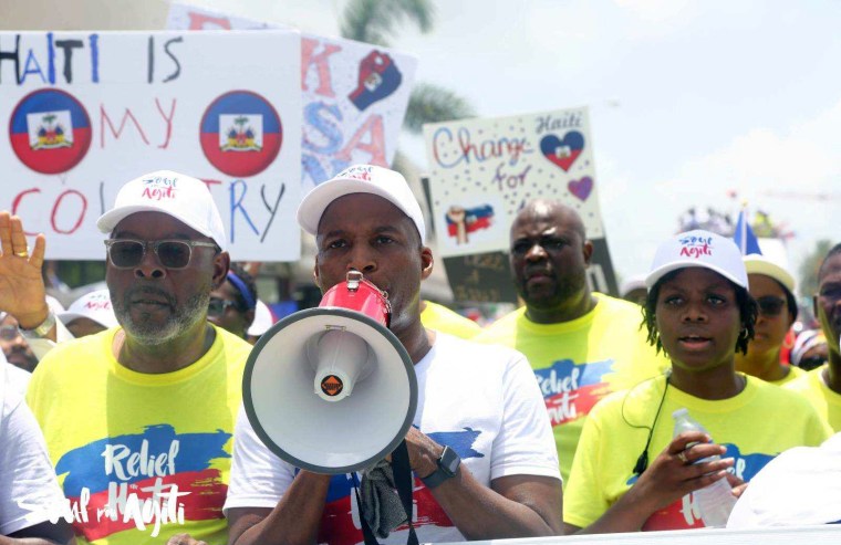 Pastor Gregory Toussaint speaking to a crowd of supporters with a megaphone during the Relief for Haiti march in Miami, Fla.