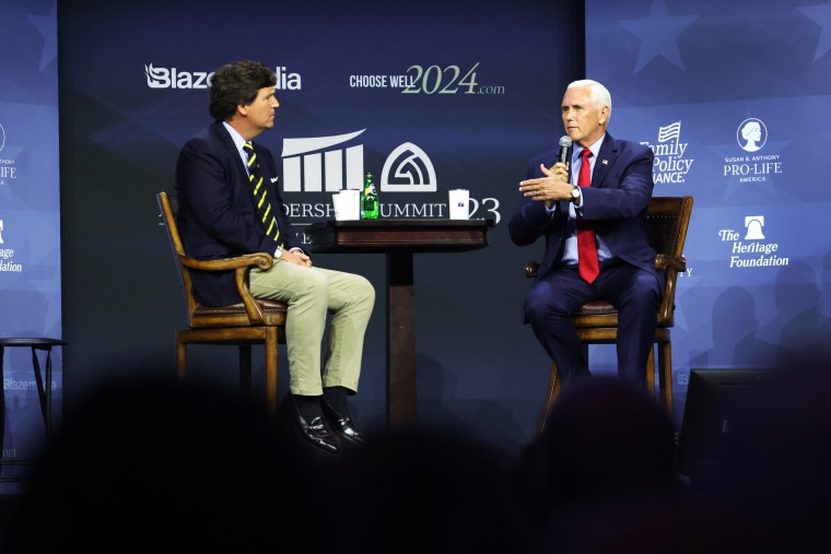 Tucker Carlson and Former Vice President Mike Pence speak onstage at a hightop table