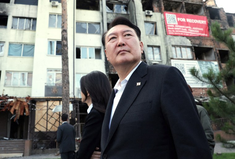 South Korean President Yoon Suk Yeol and first lady Kim Keon-hee look at damaged buildings in Irpin